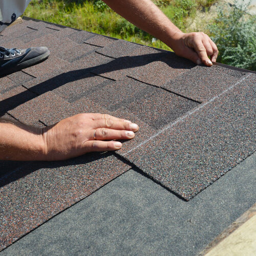 close-up of a roofer repairing a shingle roof